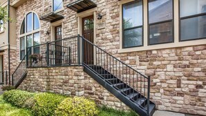 Ein Steinhaus mit Treppe, großen Fenstern und einem Balkon.
