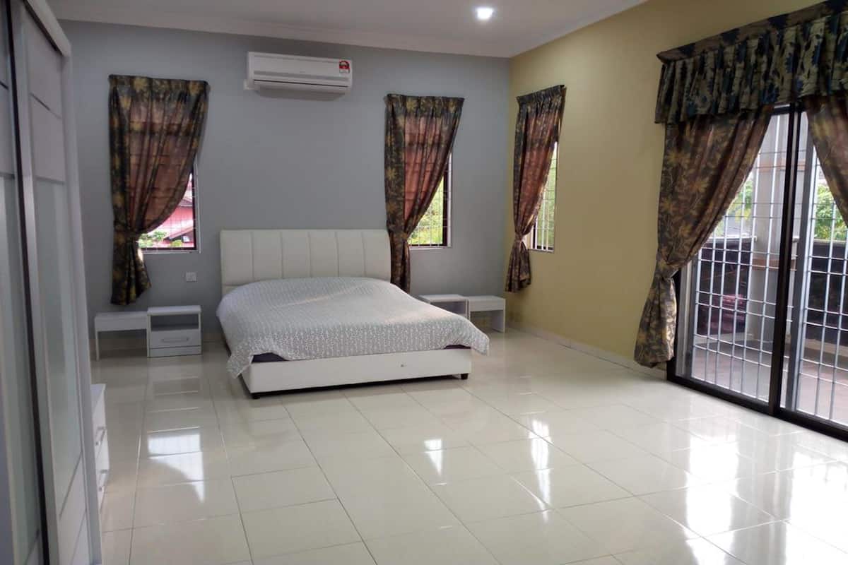 A bedroom with a bed, two bedside tables, a window with curtains, and a sliding glass door.