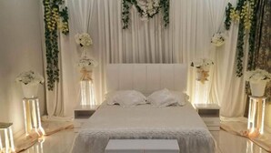 A bedroom with a large bed, white bedding, and decorative floral arrangements. - ArRayyan Guesthouse & Homestay (Taiping)