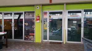 A storefront with a green facade, glass doors, and a visible menu board.