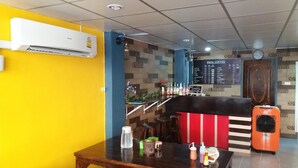 A restaurant with a bar area, a menu board, and an air conditioning unit on the wall. - Natcha Place Rangsit Donmuang (Lam Luk Ka)