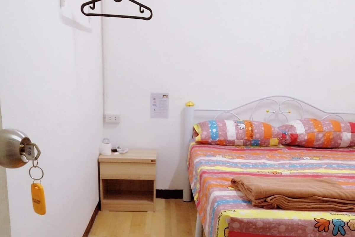 A small, clean room with a bed, a nightstand, and a hanging light fixture.