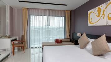 A hotel room with a large bed, a desk, a chair, a TV, and a window with curtains.