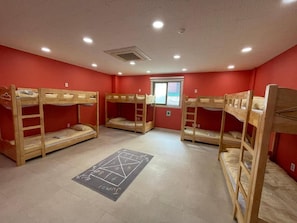 A dormitory room with bunk beds, a chalkboard with a game, and a window with a view.