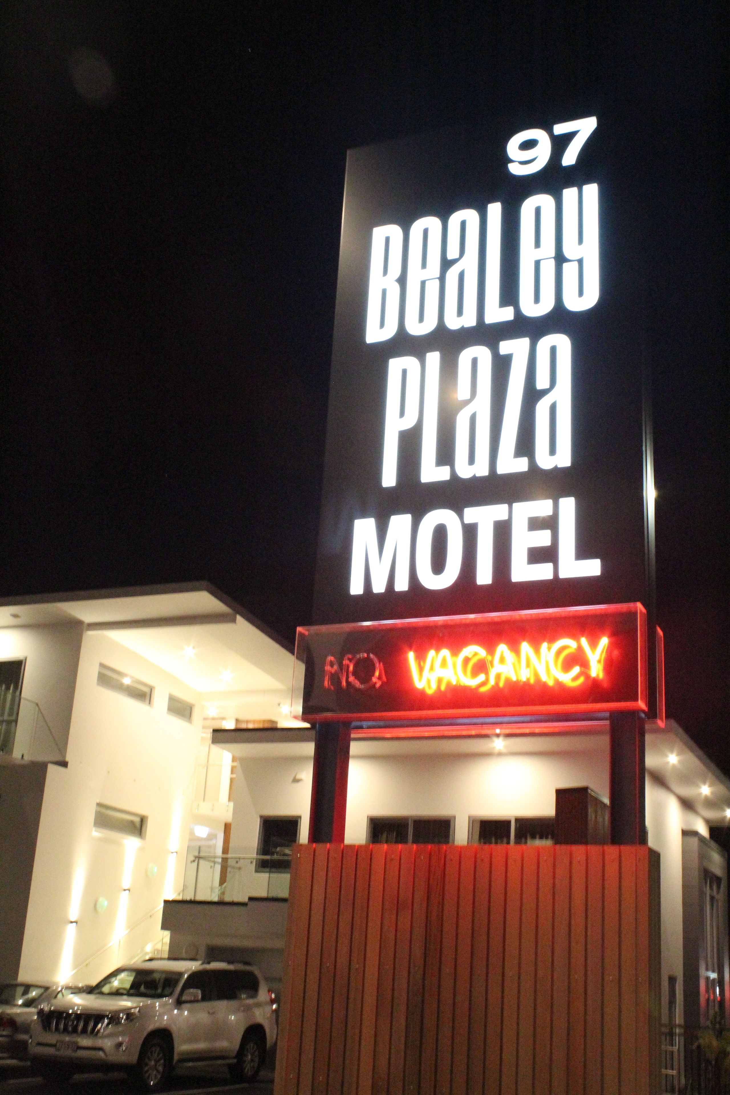 A motel sign with "97 Bealey Plaza" and "VACANCY" displayed.