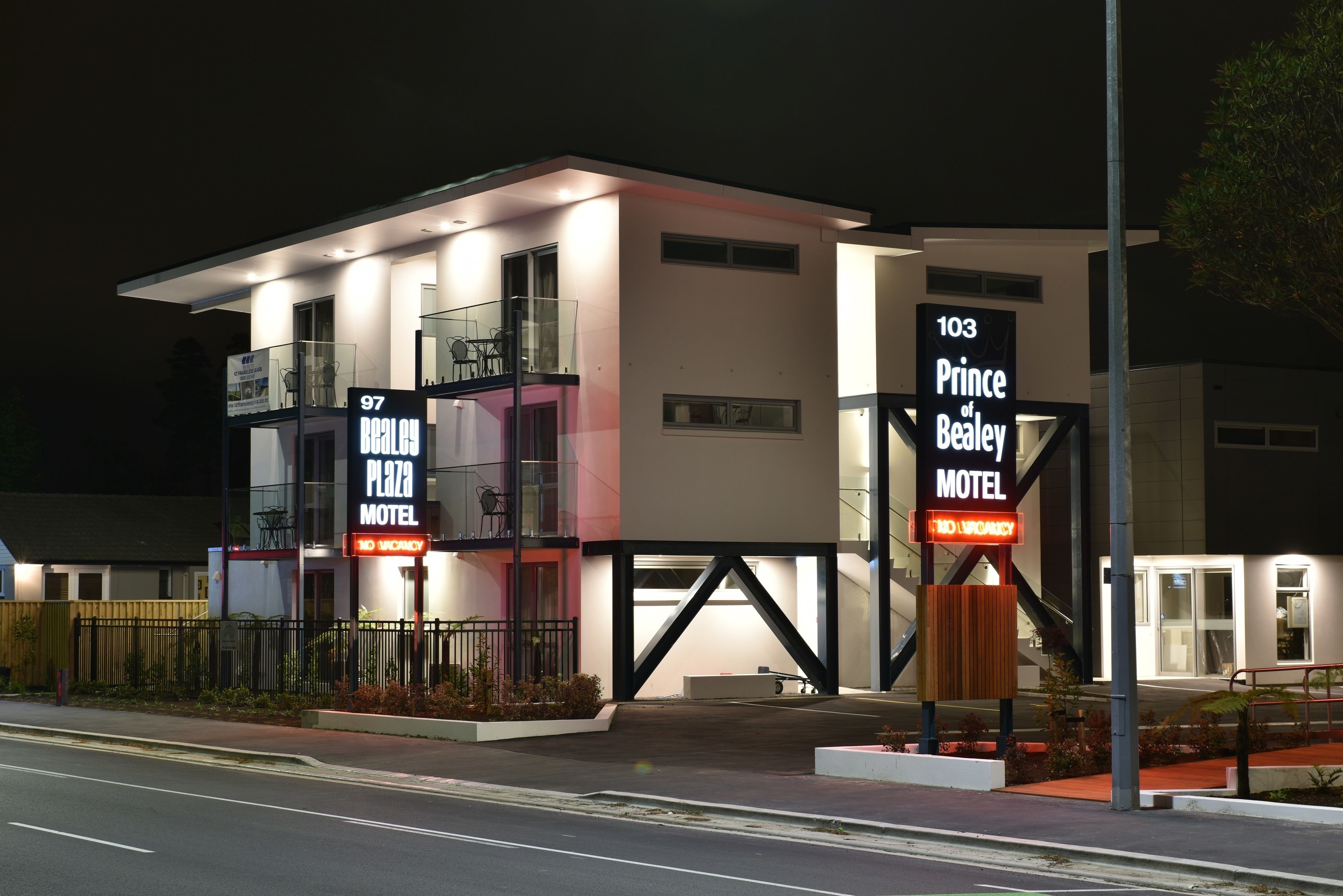 A modern motel with a sign indicating 97 Real 97 Plaza Motel and 103 Prince of Bealv Motel.