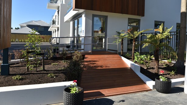 A modern building with a wooden deck, potted plants, and a clear sky. - Bealey Plaza Motel (Christchurch)