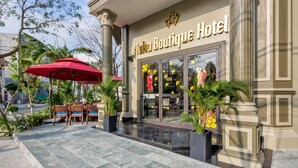 The exterior of Haku Boutique Hotel with a paved entrance, outdoor seating area, and decorative plants. - Haka Hotel & Apartment (Da Nang)