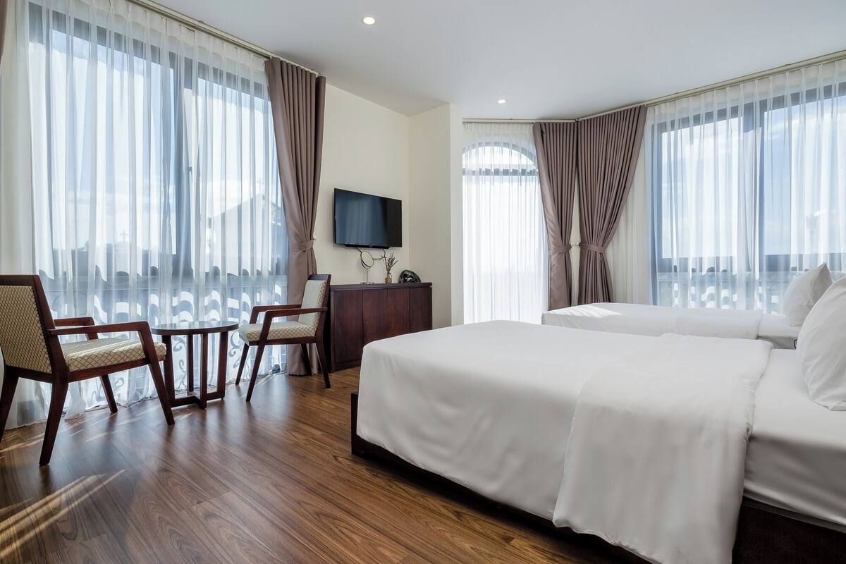 A hotel room with a large bed, a TV, a desk, and a chair.