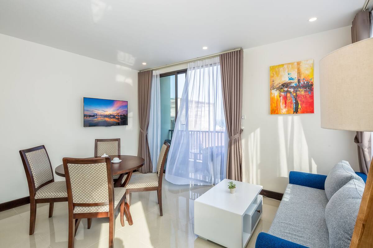 A modern living room with a sofa, dining table, chairs, and artwork on the walls.