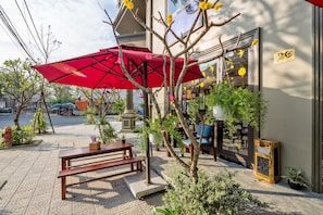 An outdoor seating area with a red umbrella, wooden benches, and potted plants.