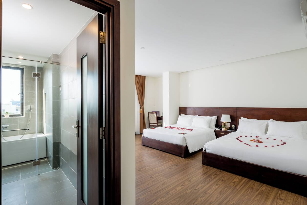 A hotel room with two beds, a shower, and a view of the city.