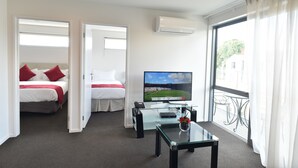 A hotel room with two beds, a TV, a glass coffee table, and a large window with a view of the outside. - 103 Prince of Bealey Motel (Christchurch)