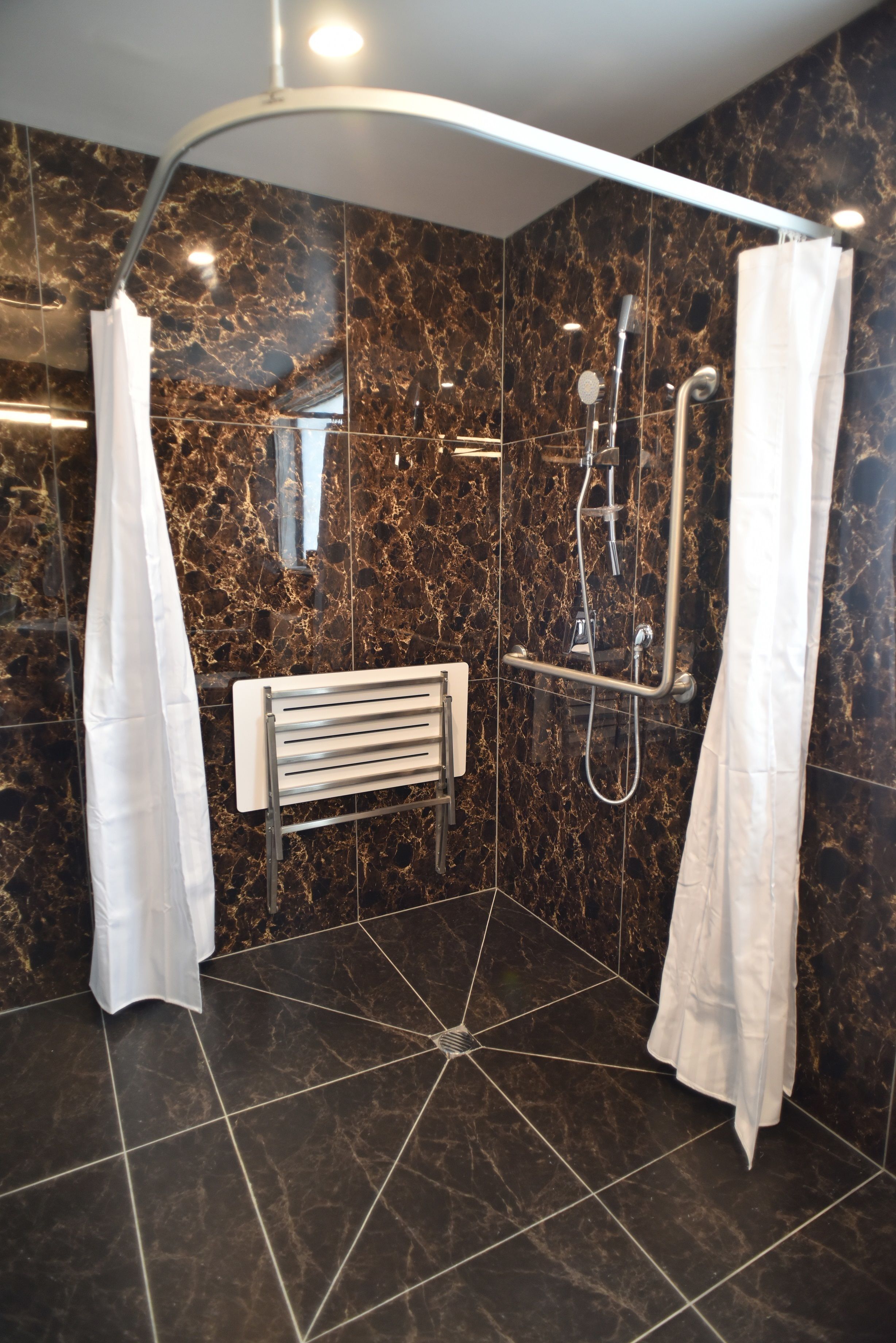 Un bagno doccia moderno con soffione curvo, doccia a mano e un ulteriore soffione a mano.