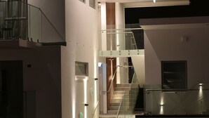 A modern interior with a glass staircase leading to a second floor, a visible door, and a lighted wall. - 103 Prince of Bealey Motel (Christchurch)