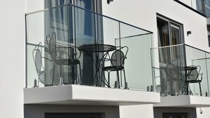 A modern building with a balcony featuring glass railings and metal chairs. - 103 Prince of Bealey Motel (Christchurch)