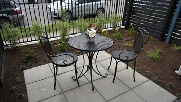 A patio with two metal chairs and a table, surrounded by a fence and a garden.