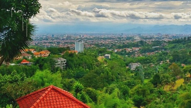 Un área de piscina en la azotea con una sombrilla roja y un pabellón con vistas a un paisaje urbano.