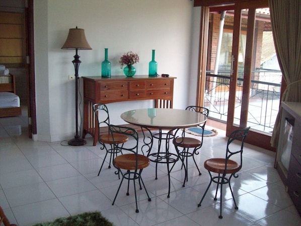 A dining area with a round table and six chairs, a wooden cabinet with drawers, and a floor lamp.