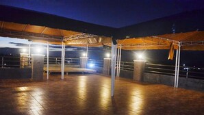 An outdoor covered area with a wooden floor, metal railings, and a canopy structure.