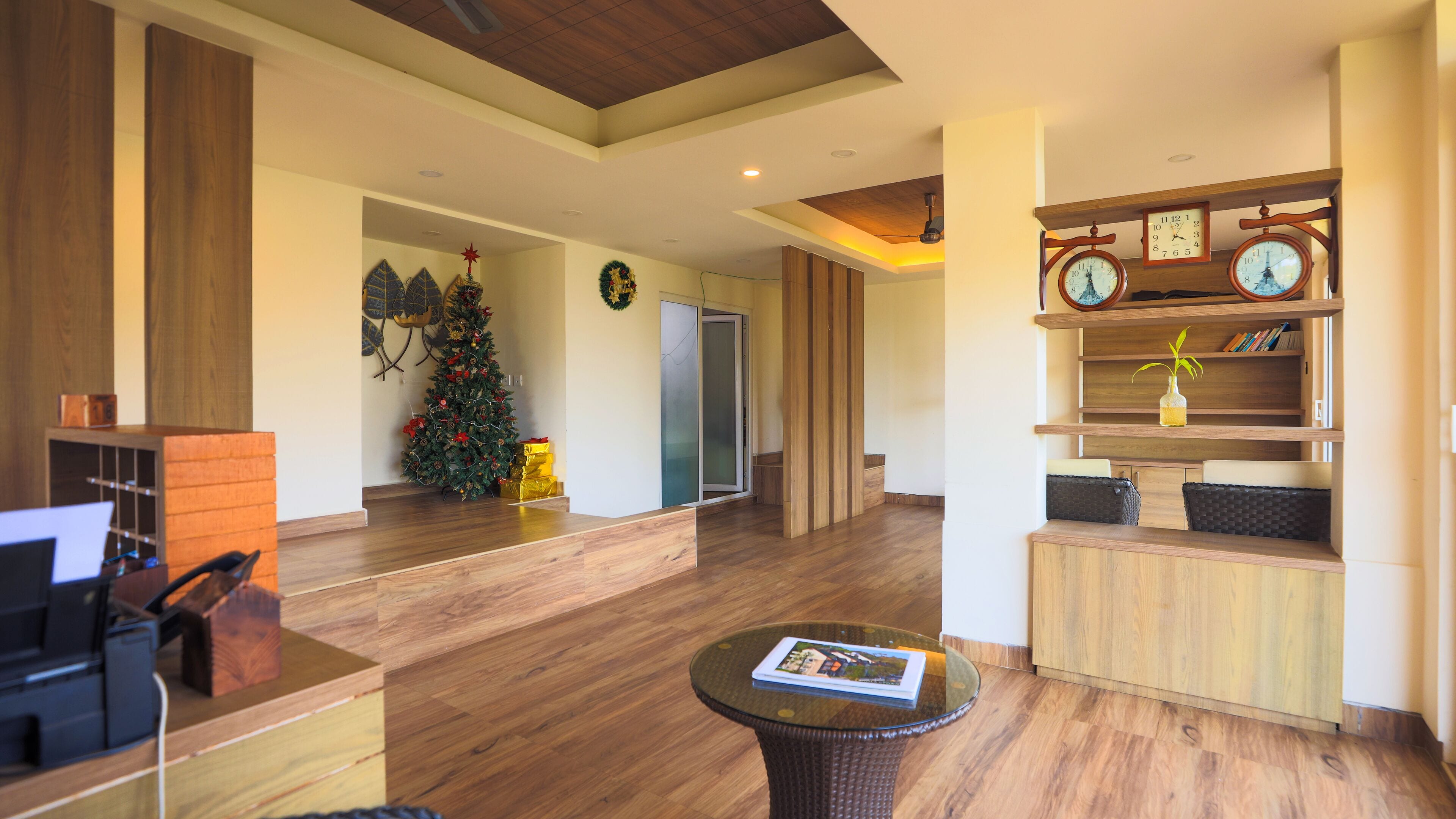 A spacious lobby with wooden flooring, a Christmas tree, and a reception desk with a computer.
