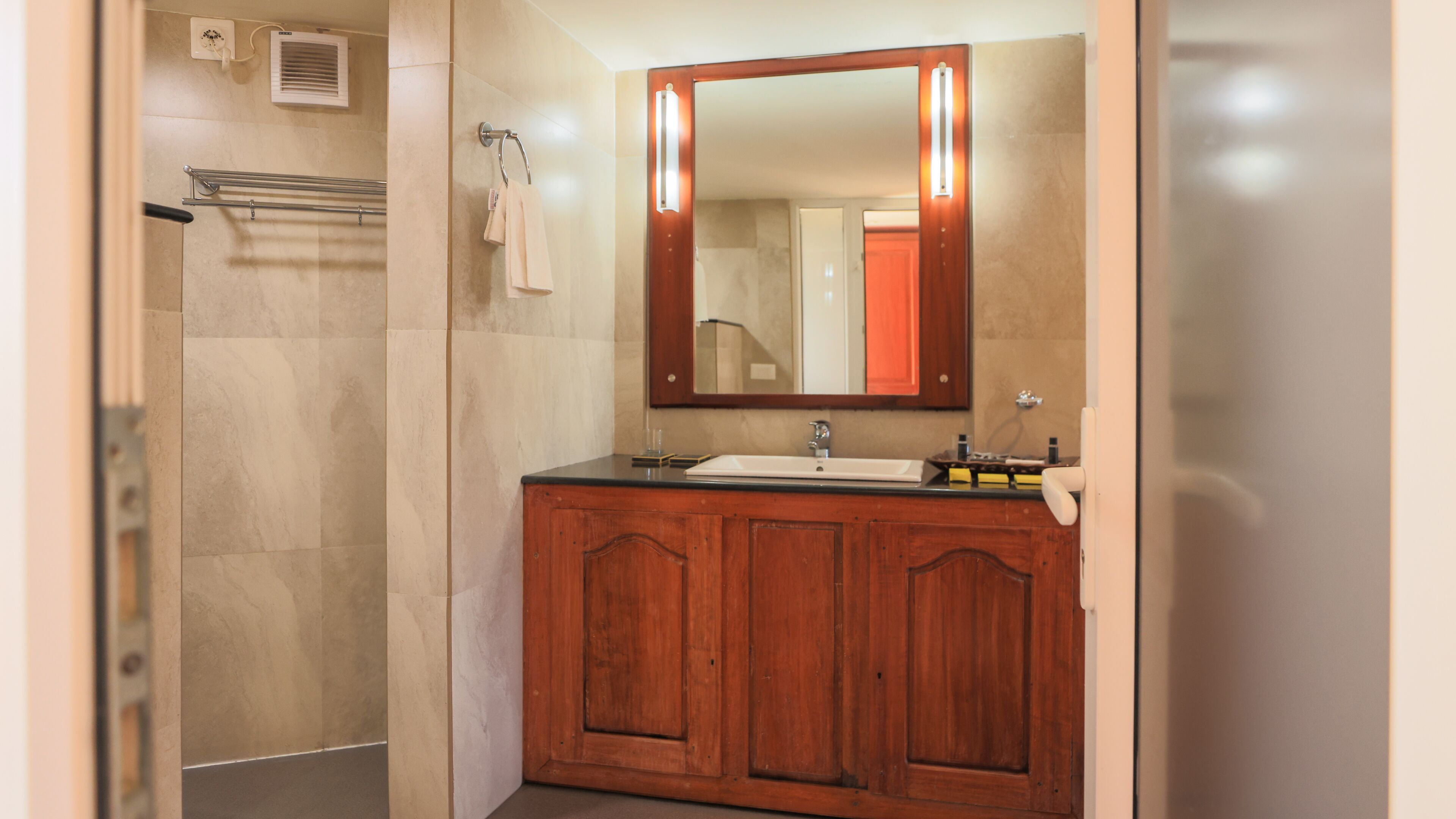 Un baño con tocador de madera, un espejo y zona de ducha.