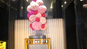 Een decoratieve bloemstelling op een metalen standaard voor een gestreepte muur.