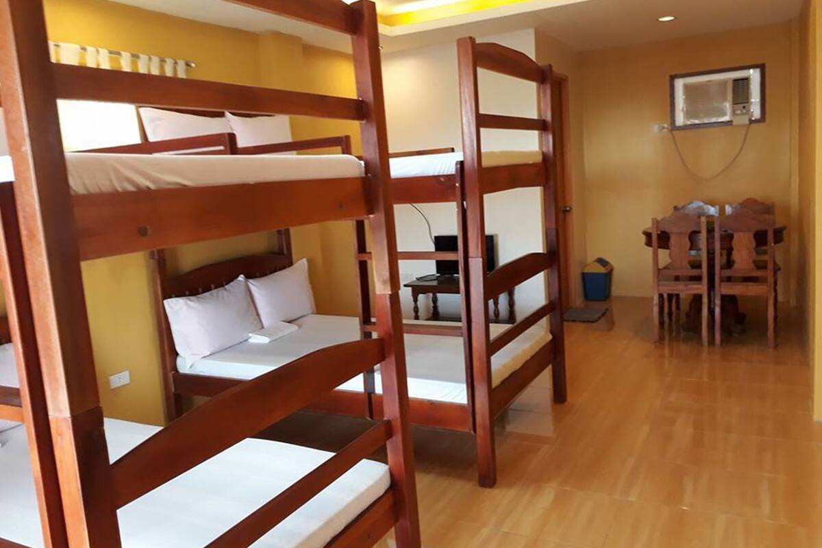 A bunk bed room with wooden frames, a desk, and a chair.