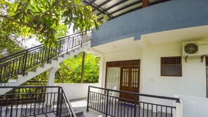 A two-story building with a staircase, a covered balcony, and a door with a traditional design. - Horizon Inn (Weligama)