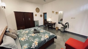 Un dormitorio con una cama, un escritorio, una silla, un armario y un sillón rojo.