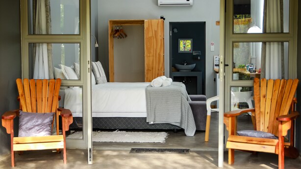 Une chambre à coucher avec un lit, deux chaises en bois, un lavabo et une fenêtre.