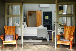 Ein Schlafzimmer mit einem Bett, zwei Holzstühlen, einem Waschbecken und einem Fenster.