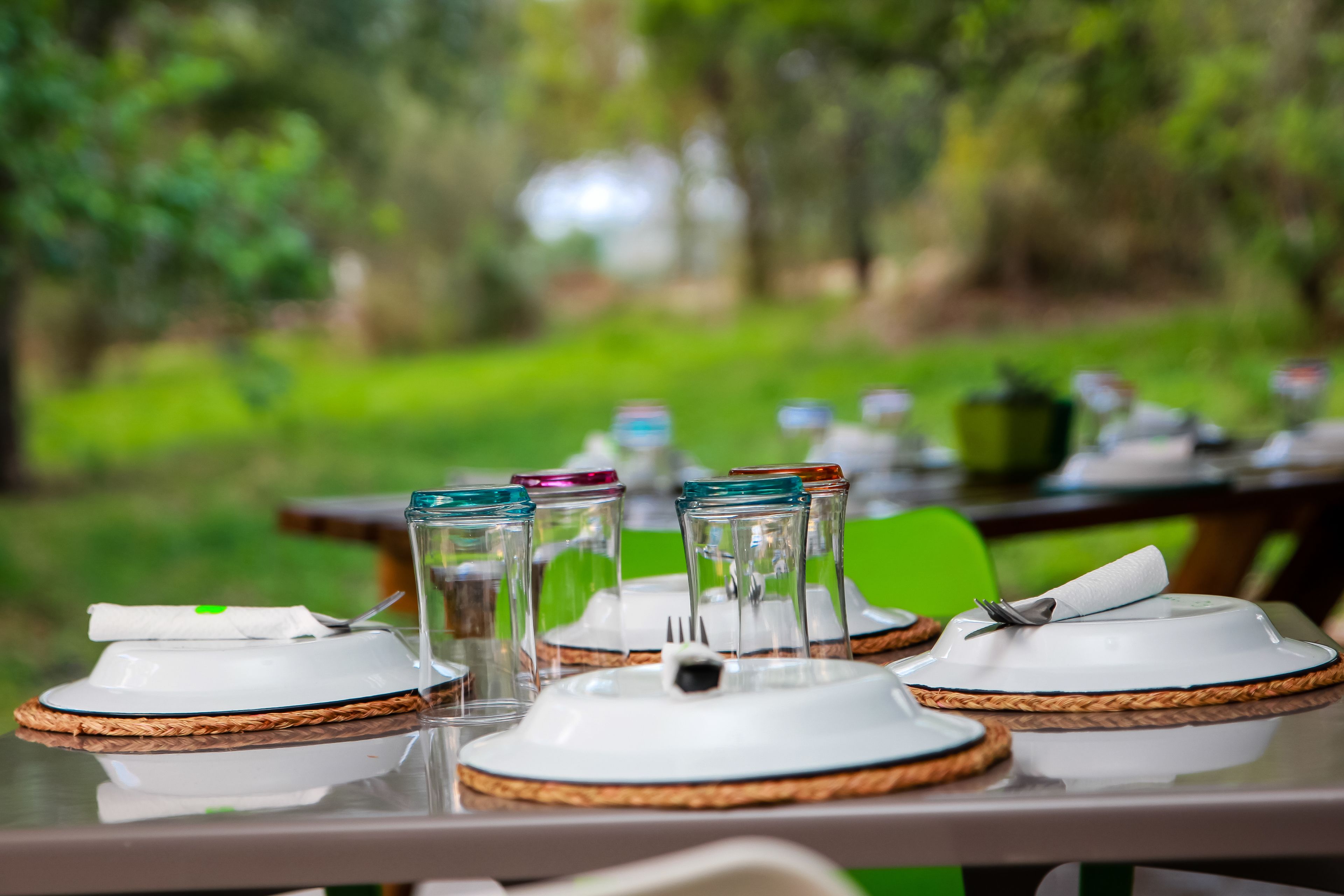 A table set outdoors with plates, glasses, and a napkin.