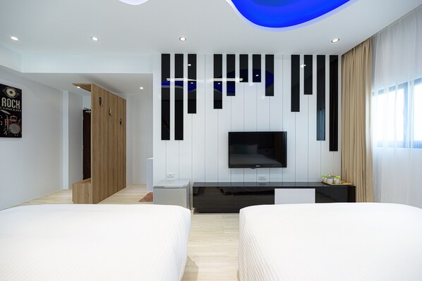 Una habitación de hotel moderna con una televisión de pantalla plana en la pared, un armario de madera y dos camas.