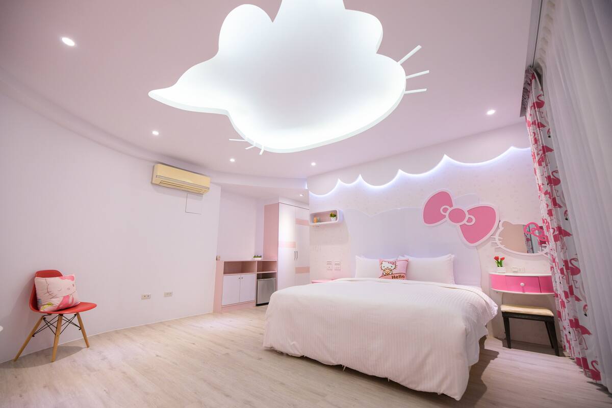 A bedroom with a bed, a chair, a vanity, and a ceiling light fixture.