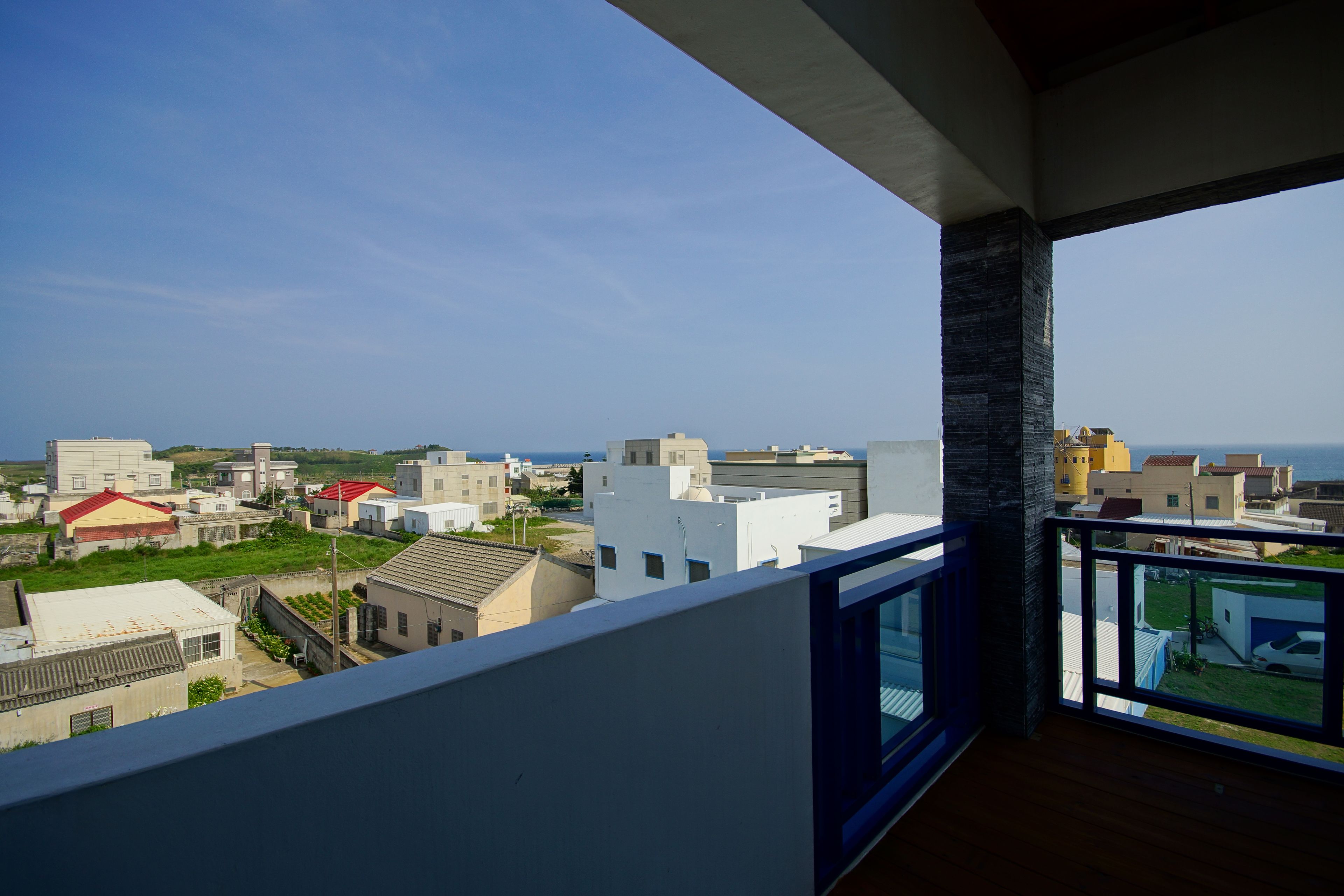 A balcony with a view of a coastal cityscape, including various buildings and a clear sky.