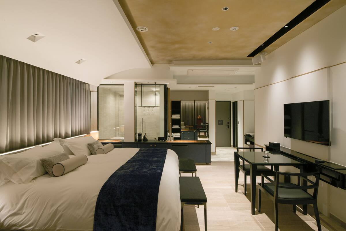 Ein modernes Hotelzimmer mit einem großen Bett, einem Schreibtisch und einem Fernseher.