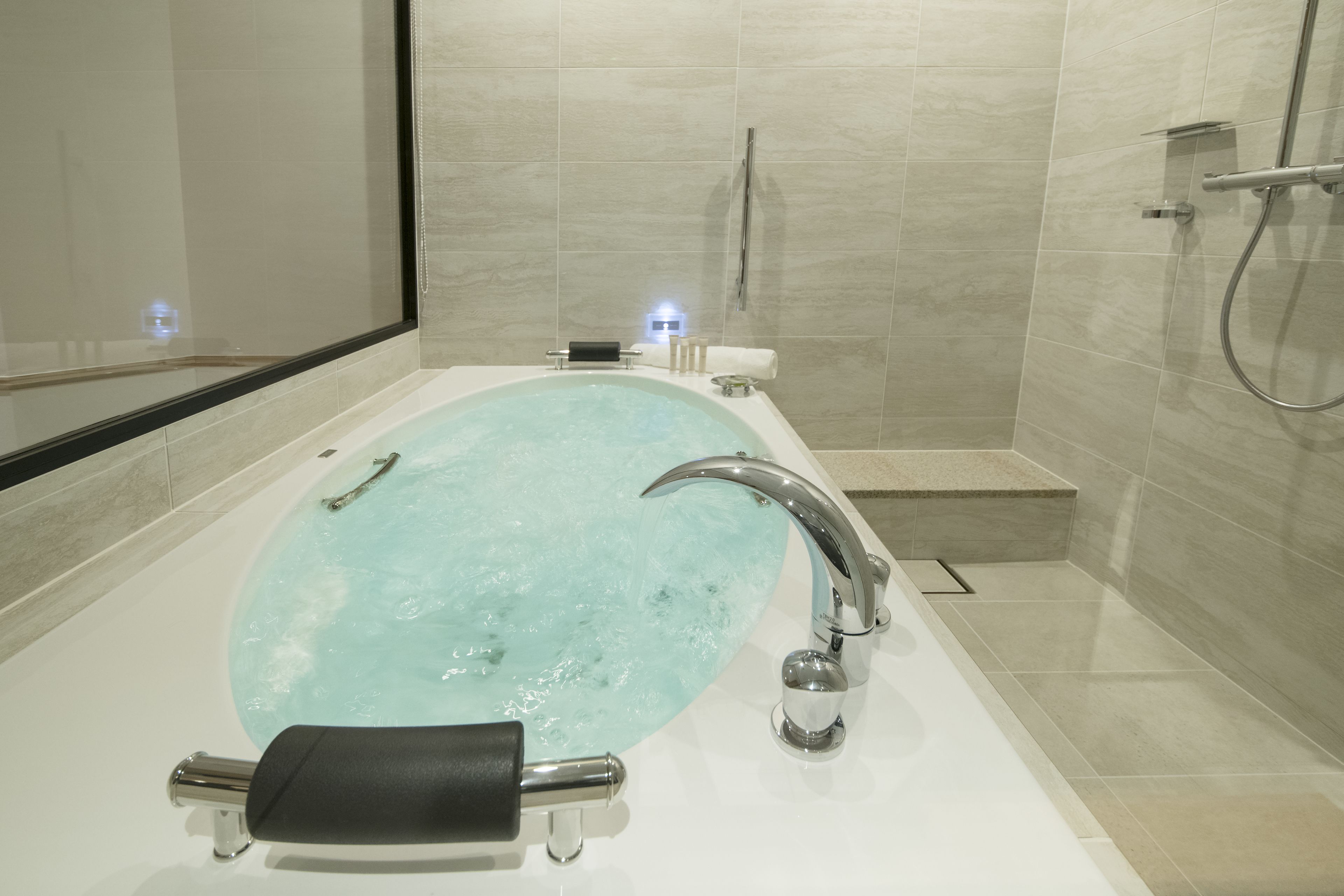 Un baño moderno con una bañera independiente, un cabezal de ducha de mano y una zona de ducha con mampara de cristal.