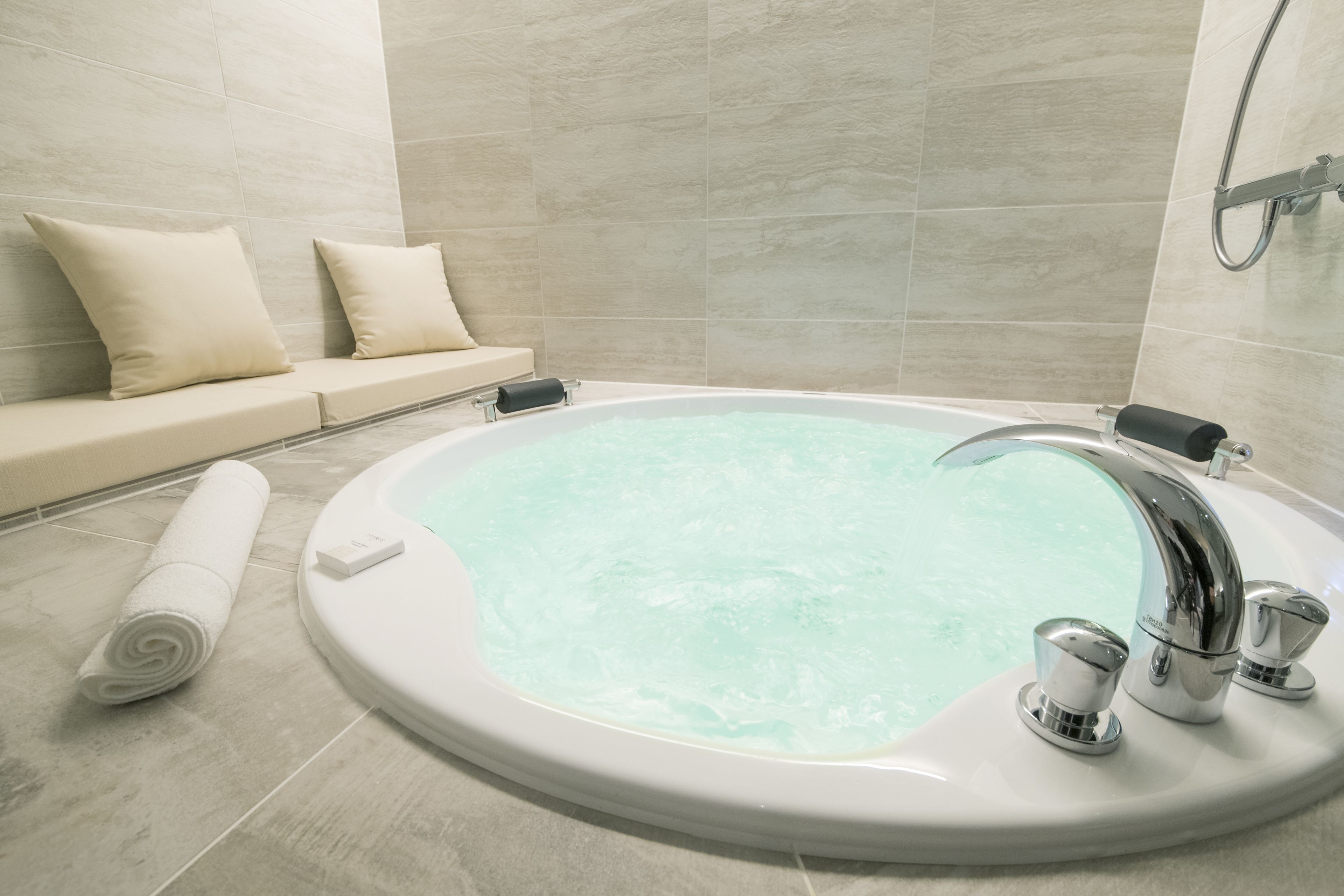 A modern bathroom with a freestanding bathtub, a towel, and a bench with cushions.