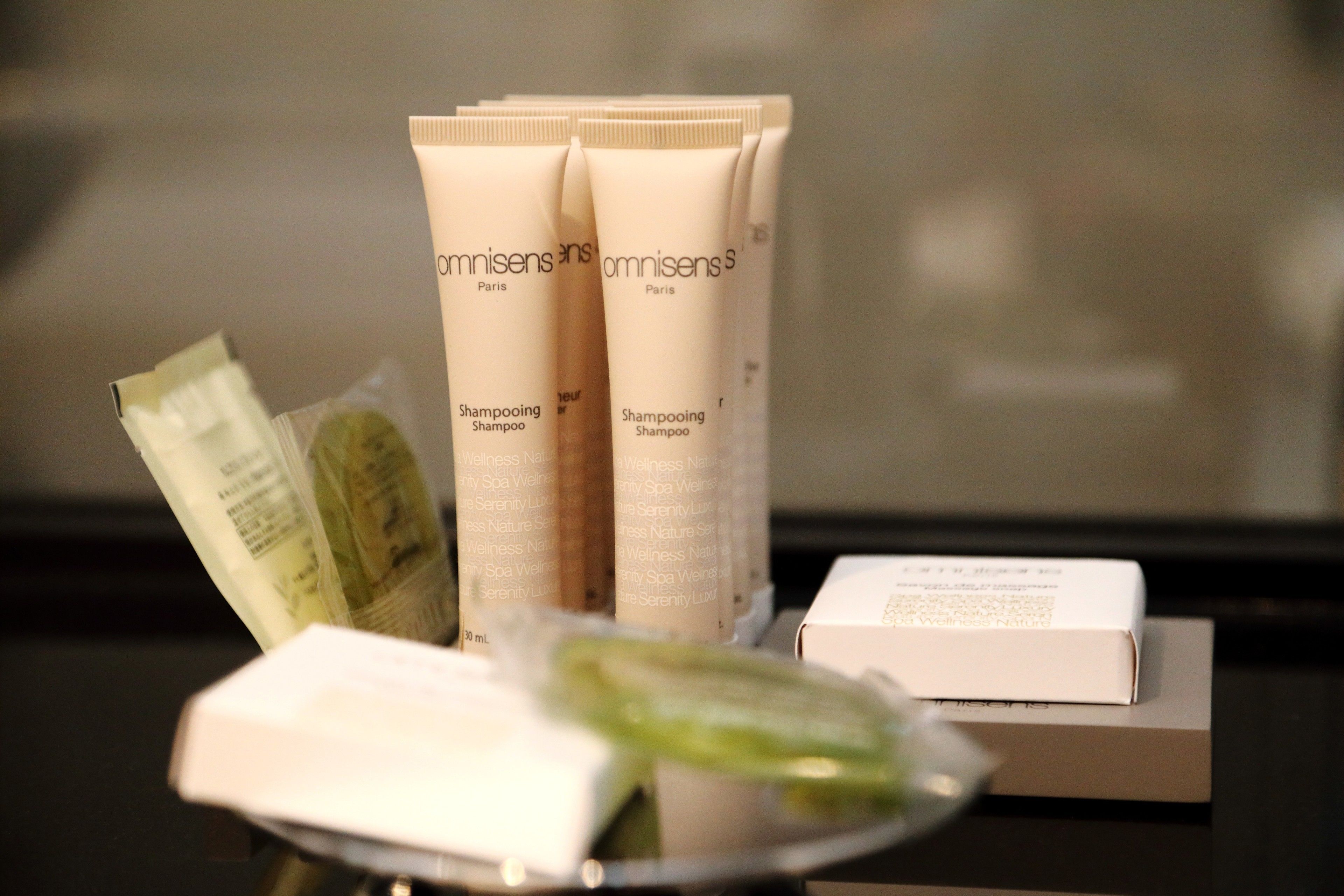 A display of Omnisens Paris shampoo products, including tubes and sachets, on a table.