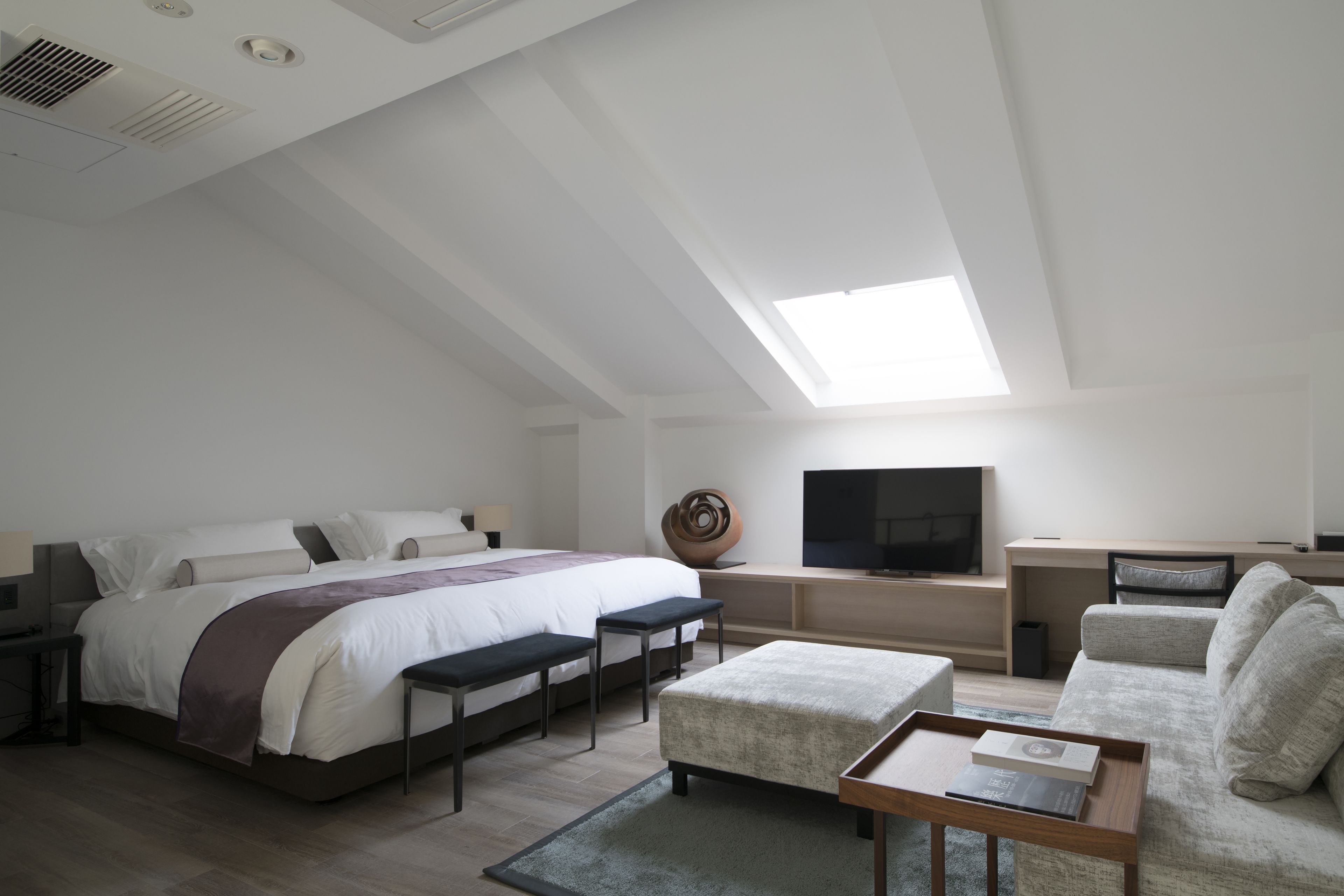 Ein modernes Schlafzimmer mit einem großen Bett, einem Schreibtisch, einem Fernseher und einem Sofa.