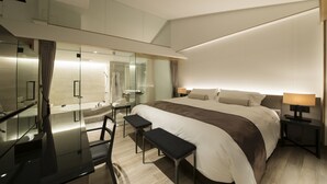 A modern hotel room with a large bed, a desk with a chair, a glass shower enclosure, and a small seating area. - Art Mon Zen Kyoto (Kyoto)