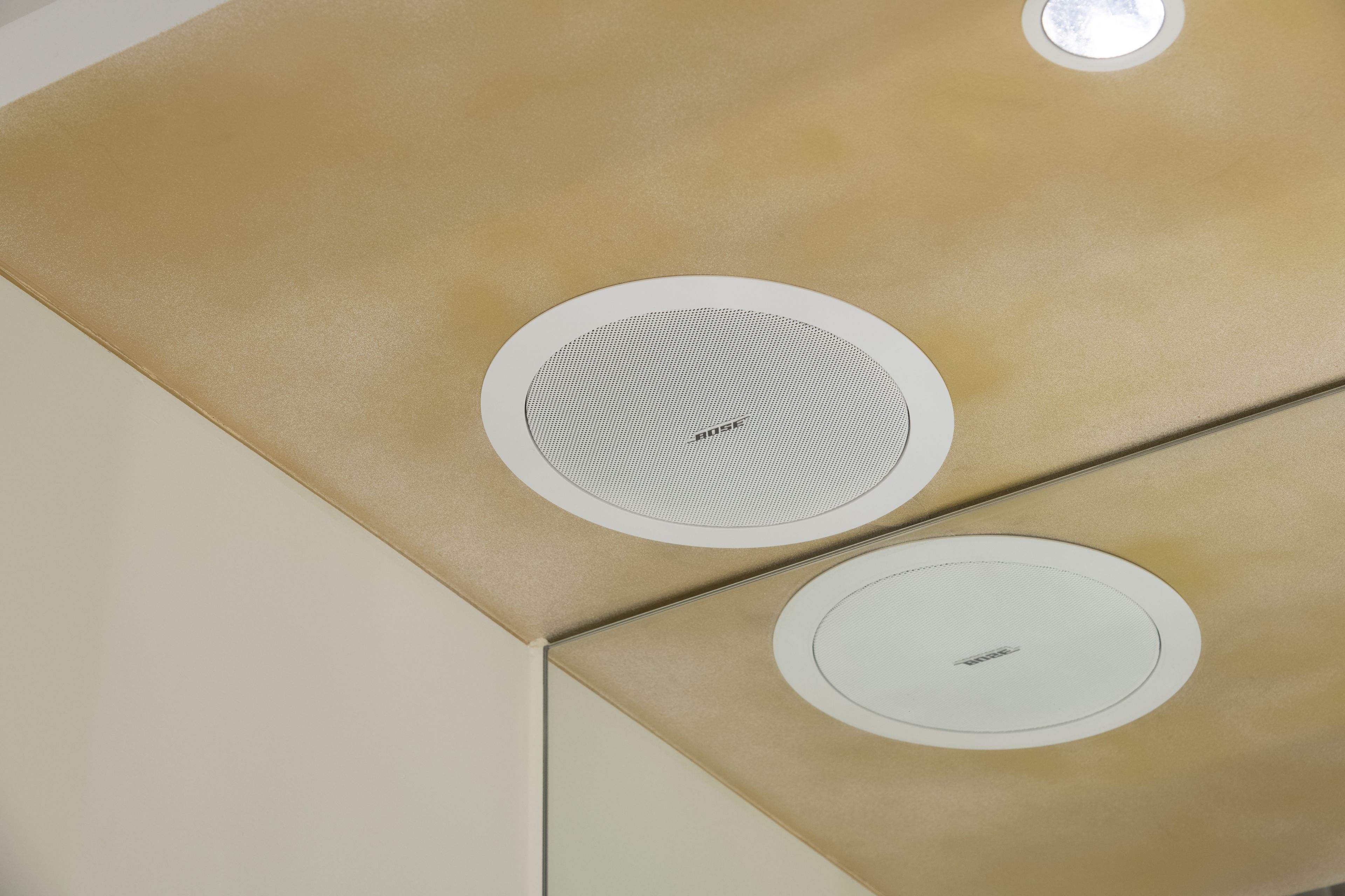 A ceiling with two circular vents and a textured panel.