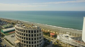 Un bâtiment situé sur la côte, de forme circulaire, et jouxtant une plage et l’océan.