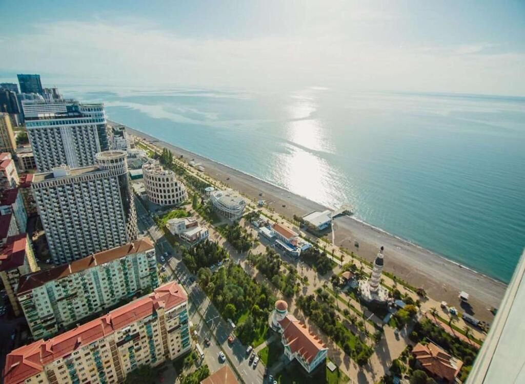 A coastal cityscape with high-rise buildings, a beach, and a clear view of the sea.