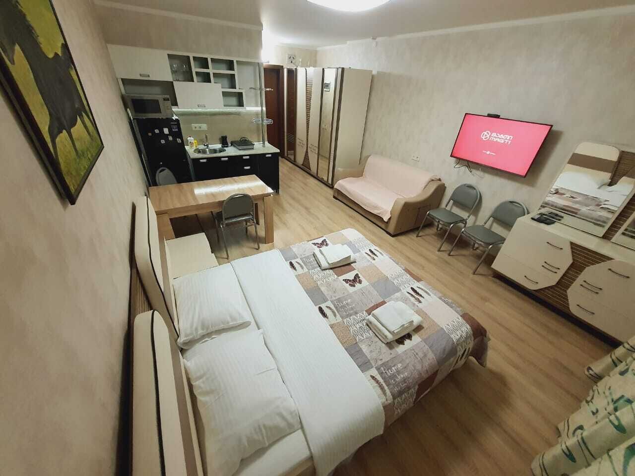 Una habitación de hotel con cama, escritorio, sofá, televisor y armario.