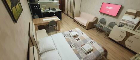Una habitación de hotel con cama, escritorio, sofá, televisor y armario.