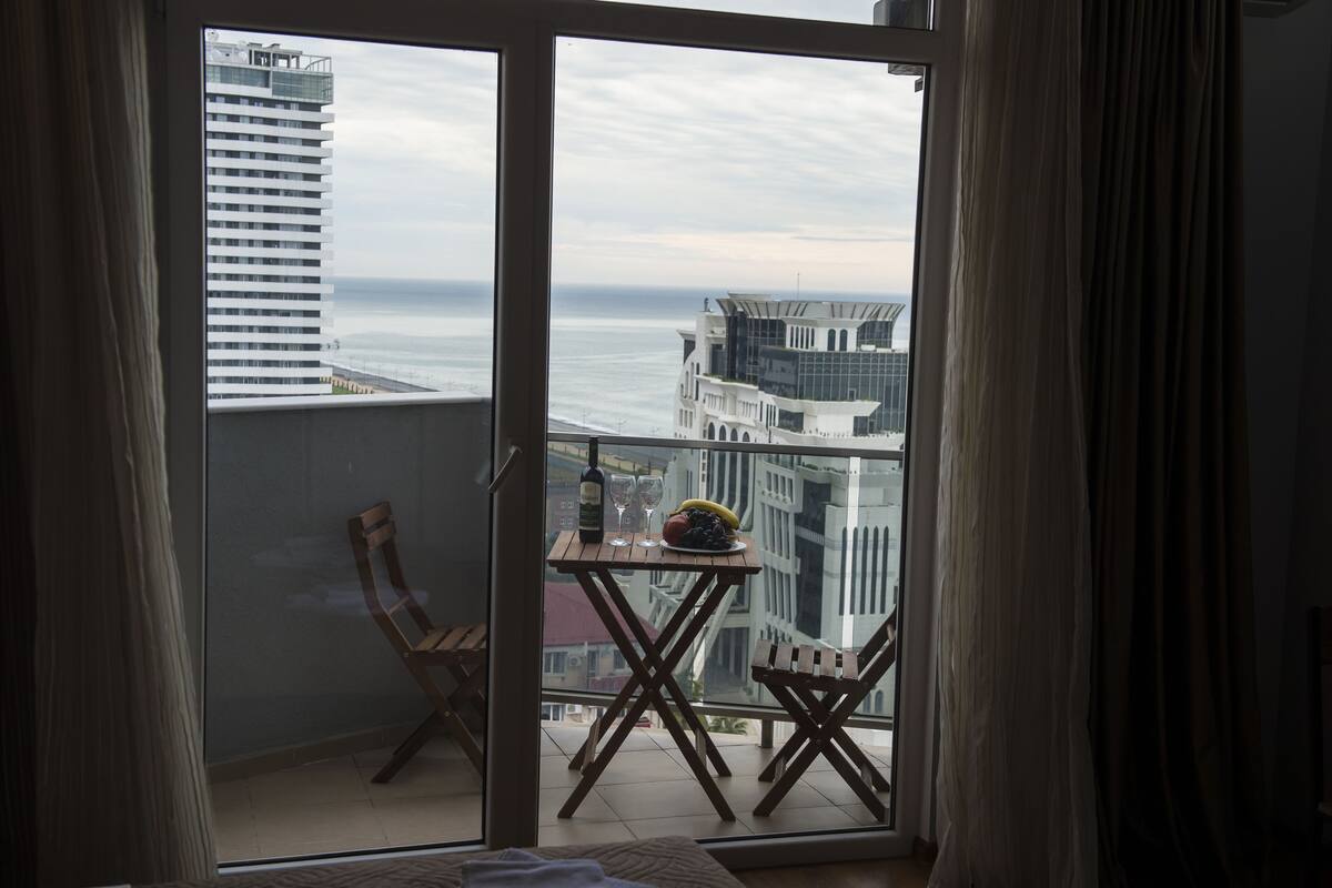 Ein Balkon mit Tisch, Stühlen und einer Weinflasche.