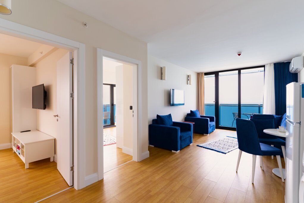 Een moderne woonkamer met een bank, stoelen, een televisie en een balkon.