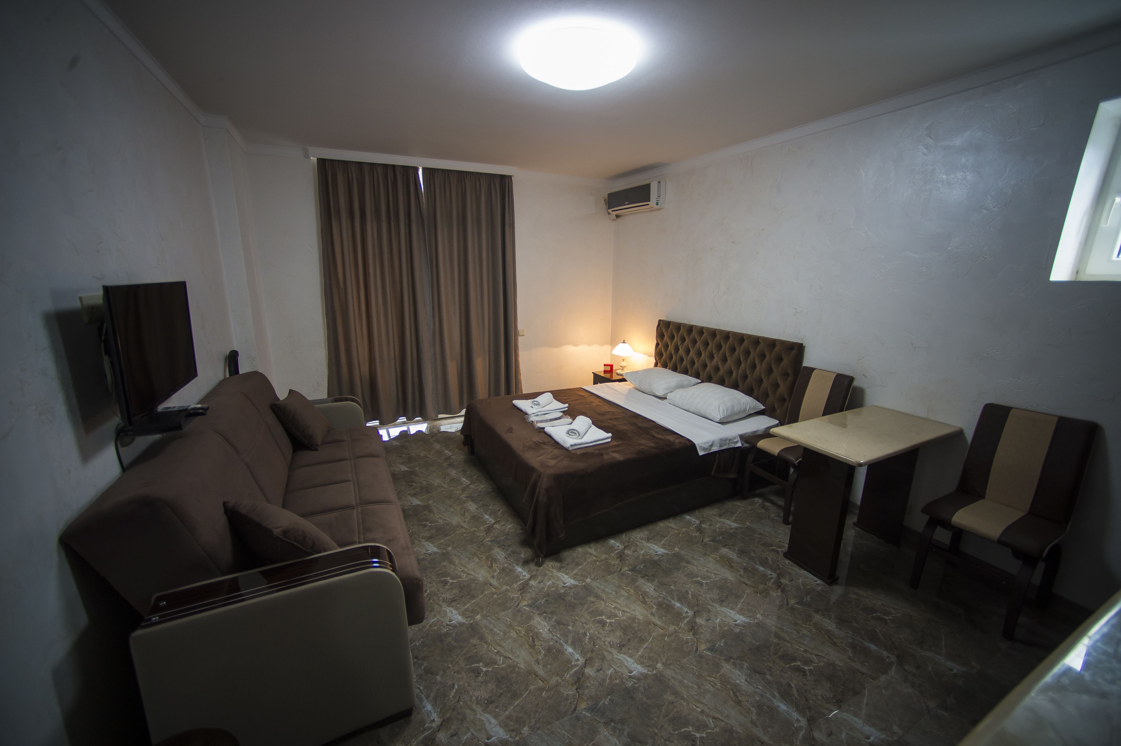 Een hotelkamer met een bed, een bank, een tafel en een televisie.
